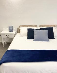马里内拉Cala Reale Rooms Marinella的一张带蓝色和白色枕头的大床和书桌