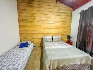 卡兰卡斯Casa Da Cléo Carrancas的一间卧室设有两张床和木墙