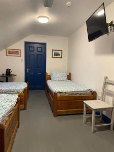 丁格尔Coastguard Lodge Hostel at Tigh TP的一间设有两张床、一台电视和一扇门的房间