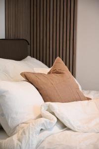 特隆赫姆Hotel feeling in the center of Trondheim的一张带白色床单和棕色枕头的未铺好的床