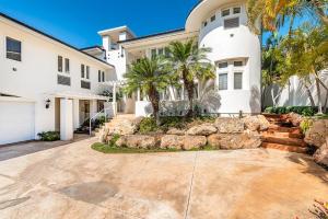 檀香山Villa Ahina的一座种植了棕榈树和车道的大型白色房屋