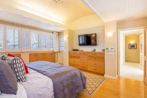檀香山Villa Ahina的一间卧室配有一张床和一台平面电视