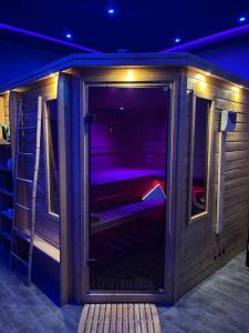 穆斯克龙Spazuroom Luxury Suite的一间室内带紫色灯的木制桑拿房