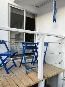 通戈伊Muelle Apart Hotel的甲板上配有2把蓝色的椅子和一张桌子