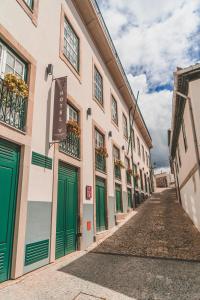 拉梅戈Douro Castelo Signature Hotel & Spa的城里一条有绿门和建筑的街道
