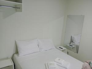 奥兰布拉Pousada Chácara VIVALLI的一张白色的床,位于一个小房间里,配有镜子