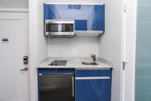 波士顿Cozy Studio on Newbury Street, #1的厨房配有蓝色橱柜、微波炉和水槽。