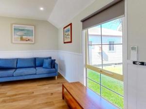 巴特曼斯贝Batemans Bay Marina Resort的客厅设有蓝色的沙发和滑动玻璃门