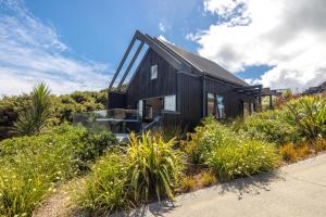 OmihaThe Guest House at Te Whau Retreat的山上的黑色房子,有植物