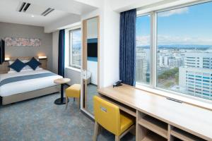 宫崎ART HOTEL Miyazaki Sky Tower的酒店客房设有一张床、一张书桌和窗户。