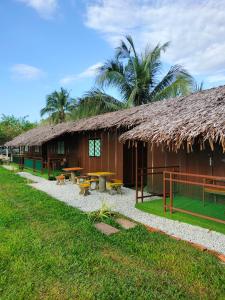 新古毛Inap Dusun Fraser Valley Kuala Kubu Bharu的一座带草屋顶和户外野餐桌的建筑