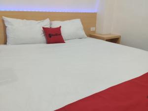 KedatonRedDoorz Syariah @ Gedong Air Lampung的一张白色的床,上面有红色枕头