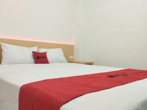 KedatonRedDoorz Syariah @ Gedong Air Lampung的卧室配有白色的床、红色床单和枕头