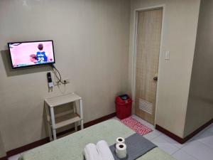 卢纳将军城#1 Green Room Inn Siargao的一间墙上配有电视的房间和红色凳子