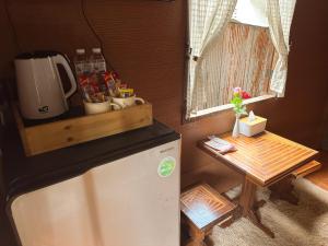 湄安บ้านพักกึ๊ดเติง แม่กำปอง เชียงใหม่的一间带冰箱和桌子的小厨房