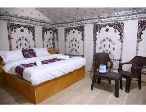 山姆Dynamic Desert Camp, Kanoi, Jaisalmer的卧室配有一张床和一张桌子及椅子