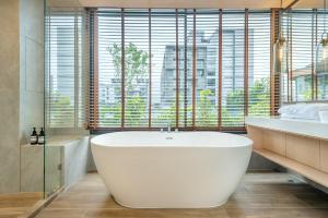 萨拉耶Salaya One Hotel & Service Apartment的一间带白色浴缸和大窗户的浴室