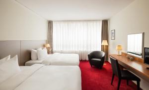 科特布斯Lindner Hotel Cottbus的酒店客房配有两张床和一张书桌
