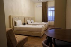 久姆里KUMA Hotel Gyumri的酒店客房带两张床、一张桌子和一张桌子。