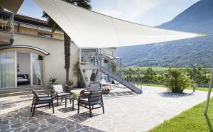 德罗Appartamenti Al Vigneto的一个带椅子和白色遮阳伞的庭院