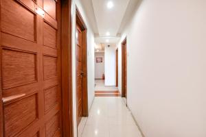 艾哈迈达巴德FabHotel Shanti Sadan Near Ellisbridge的走廊设有木门,铺有白色瓷砖地板