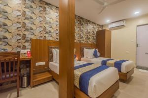 孟买Arton Regency的一间卧室设有两张床和石墙