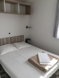 普罗普里亚诺米勒拉露营旅馆的一张白色的床,上面有两条毛巾