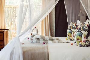 斯库库扎Umkumbe Bush Lodge - Luxury Tented Camp的一间卧室配有一张带天蓬的白色床