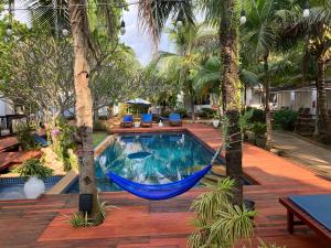 功孟海滩Isle Beach Resort Krabi-SHA的吊床挂在两棵棕榈树之间,靠近游泳池