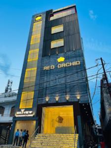 坎普尔Red Orchid Hotel Kanpur的一座红色洋葱建筑,前面的人站在