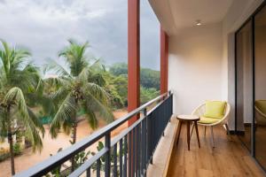 坎多林The Astor - All Suites Hotel Candolim Goa的一个带椅子的阳台,享有海滩美景