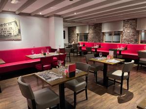斯莱纳肯Gasterij Berg en Dal的餐厅设有红色的隔间和桌椅