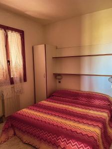 玛丽安迪安多拉VILLAGGIO ANDORA COLOMBO的小卧室配有带条纹毯子的床