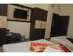 MādhavpurHOTEL MADHUVAN, Madhavpur的客房设有两张床和一台墙上的电视。