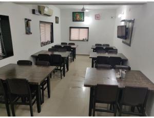 MādhavpurHOTEL MADHUVAN, Madhavpur的一间设有木桌和椅子的餐厅