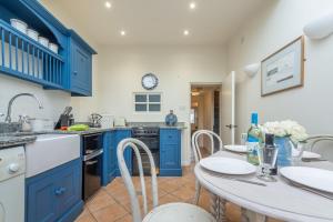 布兰克斯特Bracken Cottage的厨房配有蓝色橱柜和桌椅