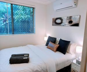 克罗纳拉Palm Garden Villa-Apt - Tropical Oasis at Cronulla Beach的卧室配有白色的床和窗户。