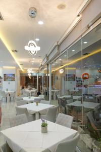 萨兰达Hotel Iliria的一间设有白色桌子和白色椅子的餐厅