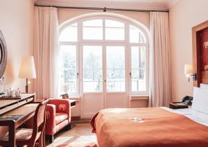 厄茂Schloss Elmau Luxury Spa Retreat & Cultural Hideaway的配有一张床、一张书桌和一扇窗户的酒店客房
