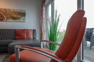 奥尔本尼兹Schleivilla Lootsen Hus by Seeblick Ferien ORO, 3Etagen,8Pers,Sauna,Kamin的客厅配有红色椅子和沙发