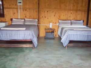 曼齐尼Inkwazi Getaway Lodge的木墙客房的两张床