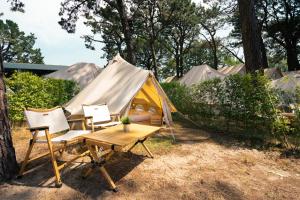 巴约讷Kampaoh Bayona Playa的帐篷配有两把椅子、一张桌子和一张长凳