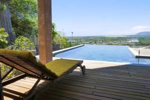 塔马兰Villa Teranga avec vue panoramique sur la baie de Tamarin的游泳池旁甲板上的椅子