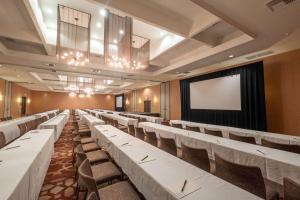 长滩玛雅酒店 - 希尔顿逸林酒店的宴会厅配有白色的桌椅和屏幕