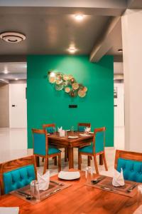 卡尔皮蒂耶Hiru Beach Resort的一间配备有桌椅的用餐室和绿色的墙壁