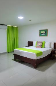 拉罗马纳Hotel Olimpo的一间卧室配有一张带绿色窗帘的大床