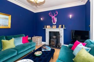 布莱尔高里Rosebank House - 12 Guests, 6 Ensuite Bedrooms, EV point, Games Rooms, Wood Burner, Pet Friendly!的蓝色的客厅设有两张绿色沙发和一个壁炉