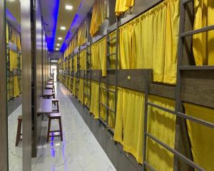 孟买Neenava Dormitory Asalpha的走廊里一排桌子,有黄色窗帘