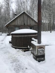 Pirts Muzejs的小木屋,地面上有雪,旁边是炉灶