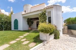 奎特里拉TAC - Vila Tina Vilamoura的一座白色的房子,设有绿门和院子